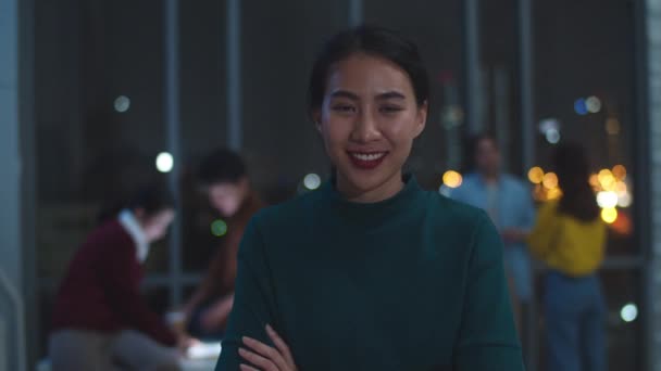 Aufgeregt lustige Geschäftsfrau Smart Casual Wear Blick in die Kamera und feiern Erfolg im Sieg, glücklich in modernen Nachtbüro Arbeitsplatz. Junge Asiatin steht entspannt im modernen Besprechungsraum.