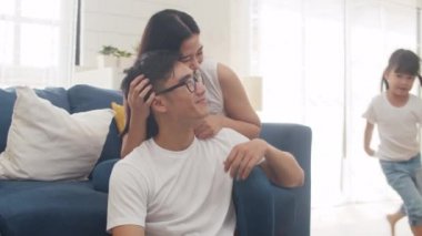 Mutlu Asyalı aile babası, anne ve kızı doğum gününde evde yerde oynaşırken eğleniyorlar. Kendini soyutlama, evde kalma, sosyal mesafeler, koronavirüs önleme için karantina.