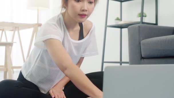年轻的韩国女士在运动服练习做运动 并使用笔记本电脑观看瑜伽视频辅导在家里 与个人培训师的远距离培训 社会距离 在线教育概念 — 图库视频影像