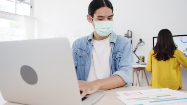 亚洲商人企业家戴着医疗面罩 在新的正常情况下与社会保持距离 以预防病毒 同时在办公室使用笔记本电脑 电晕病毒后的生活方式 — 图库视频影像