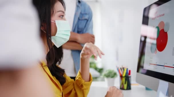 アジアのビジネスマンは 新しいプロジェクトの同僚についてのブレーンストーミングのアイデアを発表し 新しい通常のオフィスで保護顔マスクを着用します コロナウイルス後の生活と仕事 — ストック動画