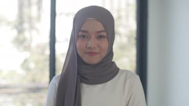Başarılı yönetici iş kadını portresi gündelik kıyafetleri kameraya bakıyor ve gülümsüyor, modern ofis işyerinde mutlu. Genç Asyalı müslüman bayan, çağdaş çalışma alanında rahatlayın..