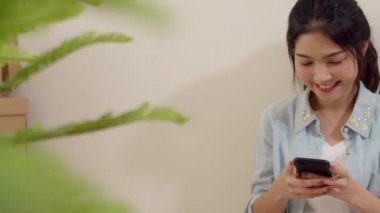 Telefon, kredi kartı ve e-ticaret interneti kullanan Asyalı bir kadın, sosyal uzaklık evde kalırken ve karantina süresi, online alışveriş, koronavirüs konsepti, oturma odasından e-ticaret interneti satın alır ve satın alır..