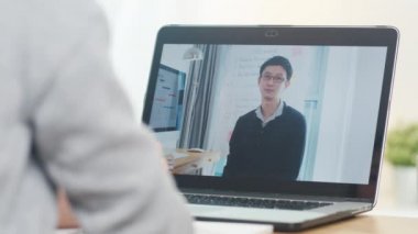 Genç Asyalı genç kız üniversite öğrencisi evde internetten erkek öğretmenle bilgisayardan öğrenme dersi alıyor. Corona virüsünün önlenmesi için sosyal mesafe ve karantina.