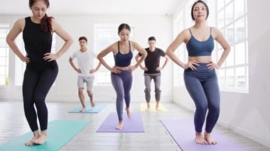 Genç Asyalı sportif çekici insanlar eğitmenle yoga dersi alıyor. Fitness stüdyosunda sağlıklı yaşam tarzı uygulayan Asya 'lı bir grup kadın. Spor aktivitesi, jimnastik ya da bale dersi.