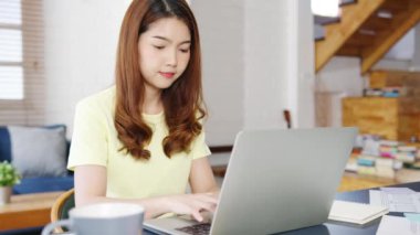 Serbest çalışan Asyalı kadınların portresi evde çalışırken dizüstü bilgisayar kullanıyor. Evden çalışmak, uzaktan çalışmak, kişisel izolasyon, sosyal uzaklık, korona virüsünün önlenmesi için karantina.