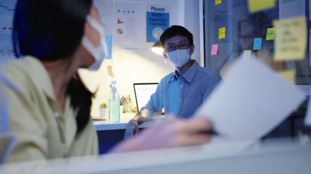 快乐的亚洲女商人戴着口罩 在新的正常情况下与他人保持距离 以防止感染病毒 她们还在办公室讨论如何在晚上与同事们一起分享工作数据 — 图库视频影像