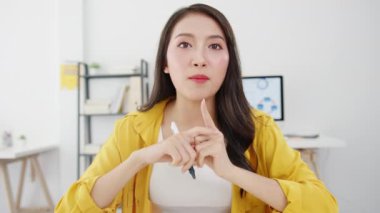 Asyalı iş kadını sosyal mesafesi virüs önleme için yeni normal bir durumda arkadaşlara kamera sunumuna bakarak ofiste çalışırken video aramasında plan hakkında bilgi veriyor. Corona virüsünden sonra yaşam tarzı.