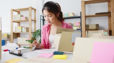 Genç Asyalı girişimci iş kadını hisse senedi alım siparişini kontrol ediyor ve merkez ofisindeki tablet bilgisayarlara kaydediliyor. Küçük işletme sahibi, çevrimiçi pazar teslimatı, yaşam tarzı serbest konsepti.