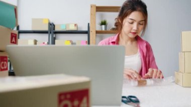 Karton kutuda ürünleri paketleyen genç Asyalı girişimci iş kadını ev ofisinde çalışan müşteriye teslim ediyor. Küçük işletme sahibi, çevrimiçi pazar dağıtımı başlat, yaşam tarzı serbest konsepti.