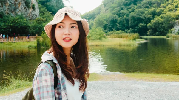 Sırt çantalı Asyalı neşeli genç gezgin bayan dağ gölünde yürüyor. Koreli genç kız mutlu bir özgürlük hissederek tatil macerasının tadını çıkarıyor. Yaşam tarzı seyahati ve boş zaman konseptinde rahatlama.