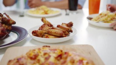 Masada yakın çekim pizza, genç arkadaşlar grubu öğle yemeği yiyor evde oturup bir porsiyon alıyorlar. Asya ailesi yemek masasında yemek yiyor. Tatil ve beraberliği kutluyoruz..