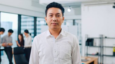 Başarılı yönetici iş adamının portresi. Modern ofis işyerinde kameraya bakıp gülümseyen şık giyimli. Genç Asyalı adam çağdaş toplantı odasında duruyor..