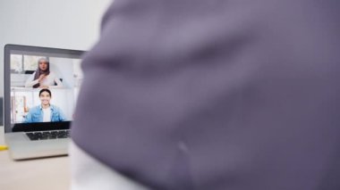 Dizüstü bilgisayar kullanan Asyalı Müslüman iş kadını, evdeki oturma odasında uzaktan çalışırken online beyin fırtınası denilen toplantı planıyla ilgili iş arkadaşına konuştu. Corona virüsü için sosyal uzaklık, karantina