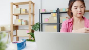 Genç Asyalı girişimci iş kadını hisse senedi alım siparişini kontrol ediyor ve merkez ofisindeki bilgisayar işine kaydediliyor. Küçük işletme sahibi, çevrimiçi pazar teslimatı, yaşam tarzı serbest konsepti.