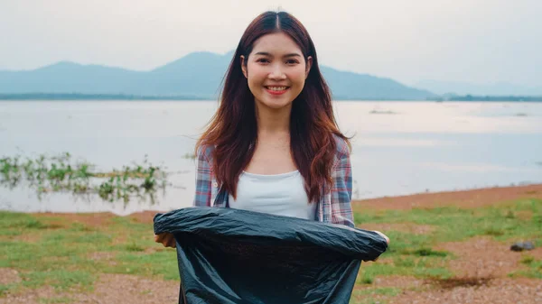 年轻的亚洲女性志愿者的肖像有助于让大自然保持清洁 看着相机 带着黑色垃圾袋在海滩上微笑 环境保护及污染问题的概念 — 图库照片