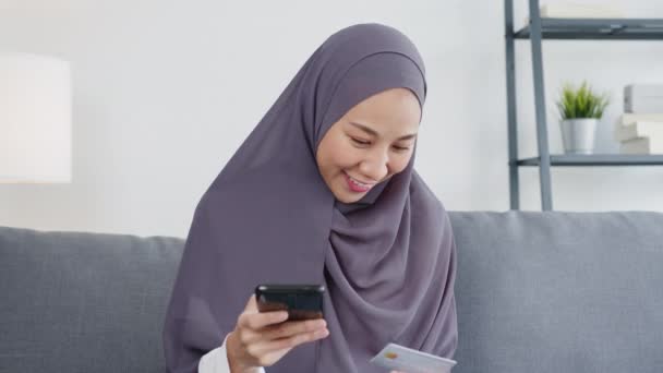 アジアのイスラム教徒の女性は 自宅のリビングルームでスマートフォン クレジットカードの購入や電子商取引インターネットを使用しています 自宅での滞在 オンラインショッピング 自己分離 社会的距離 コロナウイルスの隔離 — ストック動画