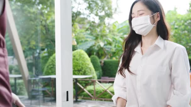 年轻的亚洲女顾客戴着面具 做着非接触式手机付款 并从咖啡店的餐厅工作人员那里拿食物袋定单 电晕病毒概念后的生活方式新常态 — 图库视频影像