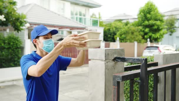 年轻的邮递员戴着面罩处理食物盒 送到顾客家里 而亚洲女性则在户外接收包裹 电晕病毒概念后的生活方式新常态 — 图库视频影像