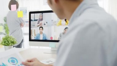 Asyalı iş adamları, iş arkadaşlarıyla yeni normal ofiste yapılacak video görüşmesi planlarını tartışarak masaüstü sohbetlerini kullanıyorlar. Corona virüsünden sonra yaşam tarzı sosyal uzaklık ve çalışma.