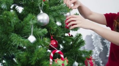 Noel ağacında süslerle süslenmiş Asyalı bir kadın ve evdeki oturma odasında yeni yıl festivali. Xmas kutlaması etkinlik hazırlığı ya da kış bayramı festivali kapalı mekanda parti konsepti.