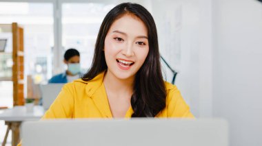 İş kadını Asyalı iş kadını sosyal mesafesi virüs önleme için yeni normal bir durum içindeyken iş arkadaşlarına bilgisayar sunumu yaparak ofiste çalışırken planlama hakkında bilgi veriyor. Corona virüsünden sonraki yaşam.