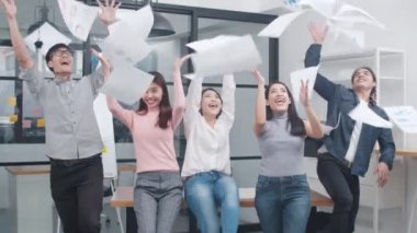 Asyalı genç yaratıcı insanlar gündelik kıyafetleriyle proje başarısını kutluyor ve belgeleri ofise atıyorlar. Başlangıçta çeşitli Asyalı erkek ve dişiler birlikte dururlar. İş arkadaşı takım çalışması konsepti.