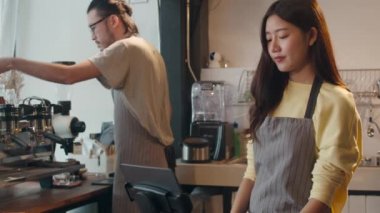 Cep telefonu ve dijital tabletle sipariş alan genç Asyalı bayan barmen, kafe restoranında cep telefonuyla müşteriyle konuşurken tezgahın arkasında duruyor. Sahip küçük işletme kavramı.