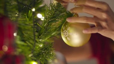 Noel ağacında süslerle süslenmiş Asyalı bir kadın ve evde yeni yıl festivali. Xmas kutlaması etkinlik hazırlığı ya da kış bayramı festivali kapalı alan partisi. Yakın çekim..