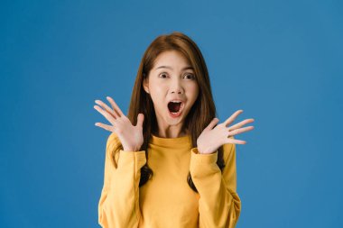 Genç Asyalı kadın mutluluğu olumlu bir ifadeyle hissediyor, neşeli sürpriz funky, günlük giysiler içinde ve mavi arka planda izole edilmiş kameraya bakıyor. Mutlu, mutlu, mutlu kadın başarıya sevinir.