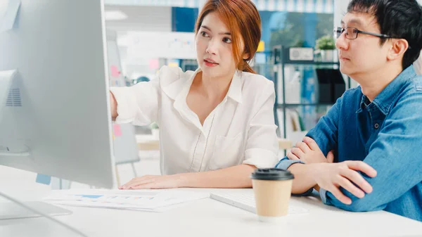 Millennial group of young Asia businessman and businesswoman in small modern urban office. Japanese male boss supervisor teaching intern or new employee korean girl helping with difficult assignment.