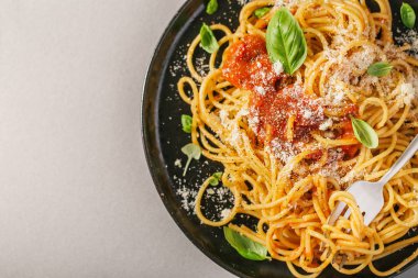 Domates soslu lezzetli iştah açıcı klasik İtalyan spagetti makarna peynir parmesan ve fesleğen plaka gri tablo üzerinde. Yukarıdan görünüm, üstten görünüm