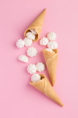 Tatlı küçük merengues pembe bir arka plan üzerinde dondurma waffle koni içinde. Kavramsal. Gıda, parti, yaz konsepti
