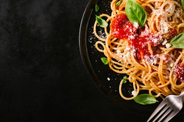 Domates soslu lezzetli iştah açıcı klasik İtalyan spagetti makarna peynir parmesan ve fesleğen plaka karanlık tablo üzerinde. Yukarıdan görünüm, üstten görünüm