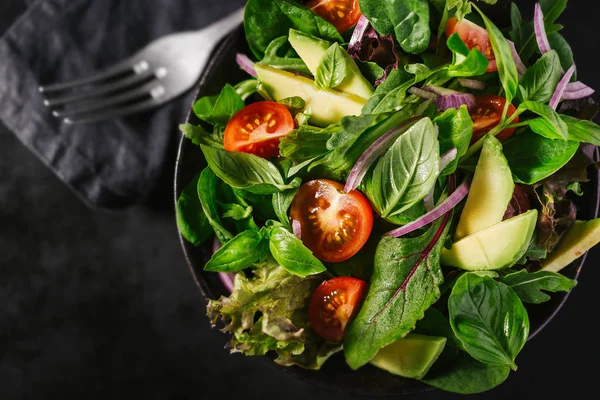 Ready served salad in bowl on dark table background. View from above. Detox Healthy Food Concept