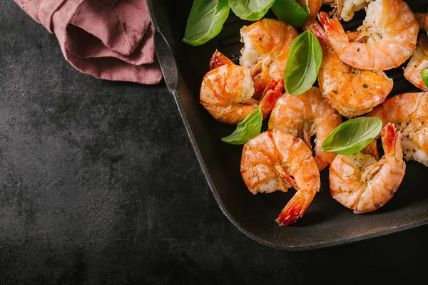 Kızarmış karides taze otlar ve fesleğen pembe Mutfak havlu ile koyu arka plan üzerinde ızgara tava üzerinde ızgara. Metin için yer ile üstten görünüm 