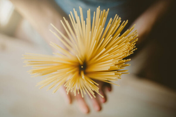 Man holding italian uncooked spaghetti, ready to cook. Closeup. Italian food or cooking concept. Selective focus 