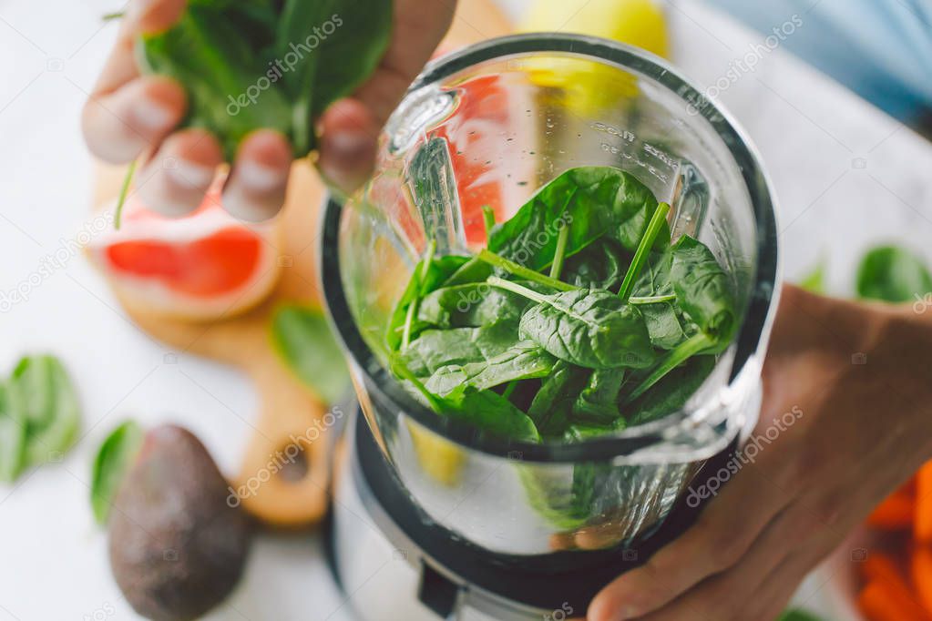 Man cooking healthy detox smoothie with fresh fruits and green spinach. Lifestyle detox concept