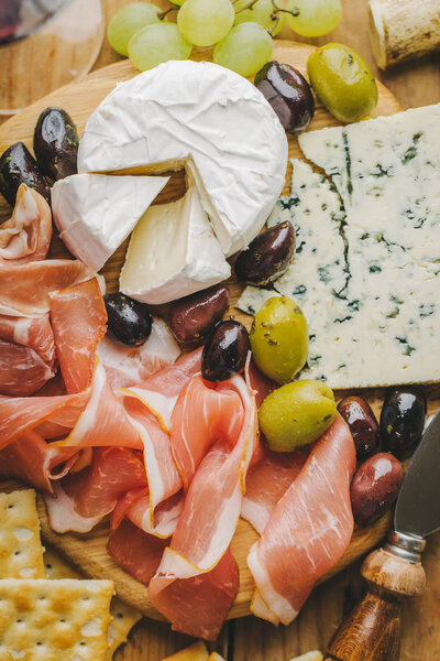 Tasty Mediterranean appetizers on old board on vintage wooden table