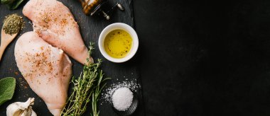 Çiğ tavuk göğsü ve malzemeler koyu siyah masada pişmeye hazır. Kopya uzayı ile yatay. Sağlıklı gıda konsepti.