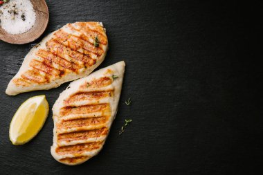 İştah açıcı ızgara tavuk göğsü siyah tahta kaplama arka planda servis ediliyor. Yukarıdan kopyalama alanı ile görüntüle
