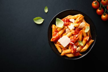 Domates sosu ve fesleğen karanlık tablo arka planda kase lezzetli iştah açıcı makarna. Servis ve yemek için hazır. Üstten görünüm 