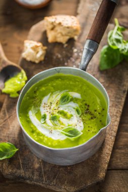 Lezzetli taze yeşil bezelye çorbası ahşap masa üzerinde tencerede pişirilir. Hizmet hazır. Portre. 