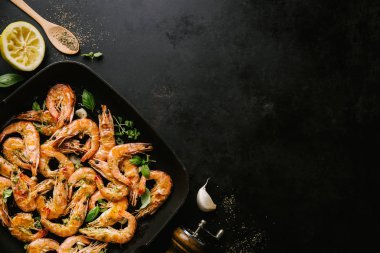 Lezzetli, kavrulmuş karides, tavada baharat ve siyah arka planda malzemeler. Kopya uzayı ile Üst Görünüm. Yemek Geçmişi İtalyan Mutfağı Konsepti
