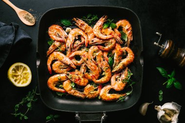 Lezzetli, kavrulmuş karides, tavada baharat ve siyah arka planda malzemeler. Kopya uzayı ile Üst Görünüm. Yemek Geçmişi İtalyan Mutfağı Konsepti
