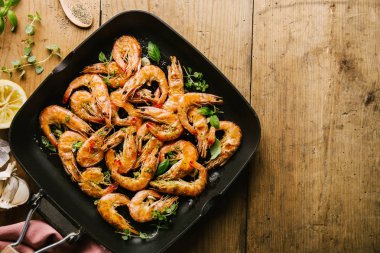 Lezzetli iştah açıcı malzemelerle ahşap masa üzerinde Pan baharatlar ile karides karides kavrulmuş. Üstten görünüm kopya alanı ile. Gıda arka plan İtalyan mutfak konsepti