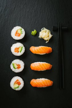 Avokado ve karanlık masada kayrak gemide somon suşi. 