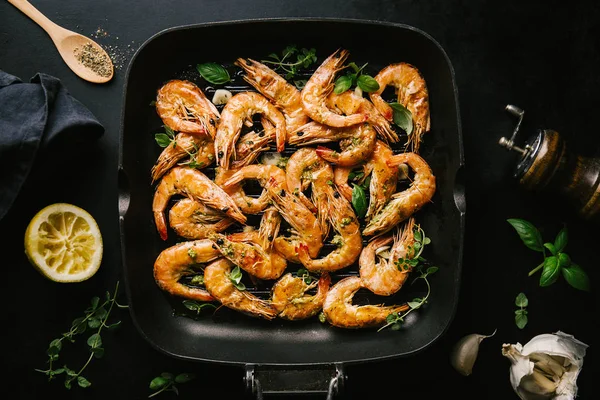 Lezzetli, kavrulmuş karides, tavada baharat ve siyah arka planda malzemeler. Kopya uzayı ile Üst Görünüm. Yemek Geçmişi İtalyan Mutfağı Konsepti
