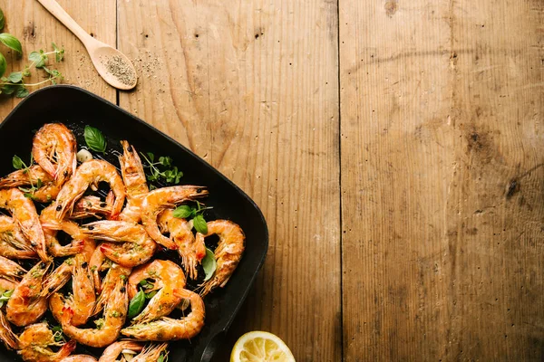 Lezzetli iştah açıcı malzemelerle ahşap masa üzerinde Pan baharatlar ile karides karides kavrulmuş. Üstten görünüm kopya alanı ile. Gıda arka plan İtalyan mutfak konsepti