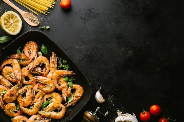 Lezzetli, kavrulmuş karides, tavada baharat ve siyah arka planda malzemeler. Kopya uzayı ile Üst Görünüm. Yemek Geçmişi İtalyan Mutfağı Konsepti